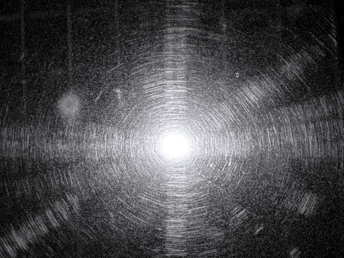 Black Mercedes hood covered in swirl marks under a shop light, before paint correction